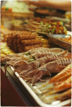 A vibrant display of fresh seafood including squid and shrimp at a bustling market.