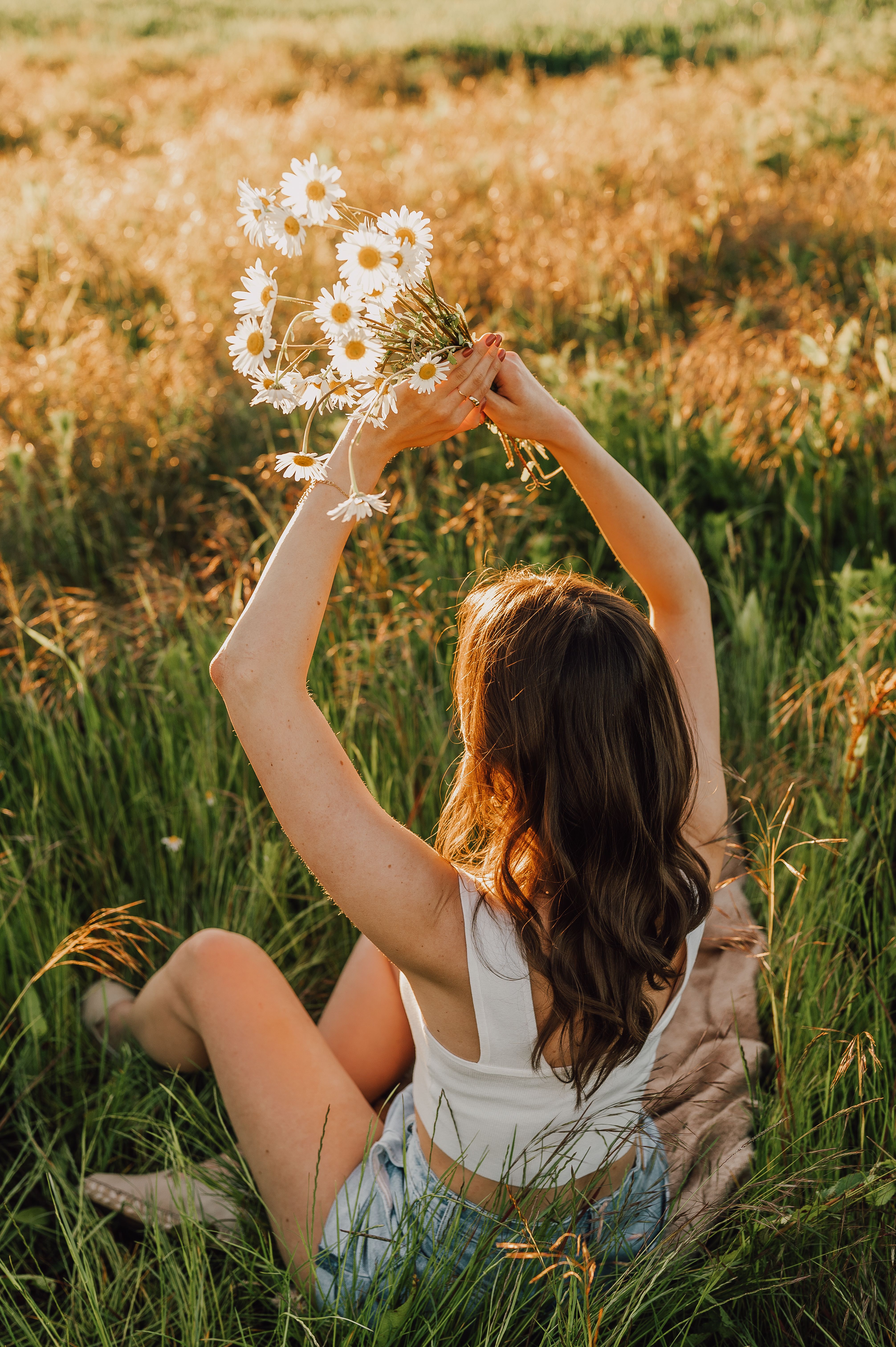 Young woman in a field holding daisies, capturing the essence of summer and nature's beauty.
