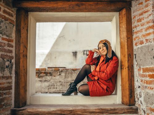 Free Woman in red jacket and aviator hat sitting in a window frame in Ciudad de México. Stock Photo