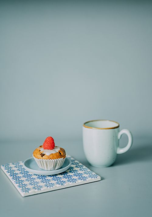 Free Elegant still life of a coffee mug and muffin with raspberry on a floral napkin. Stock Photo