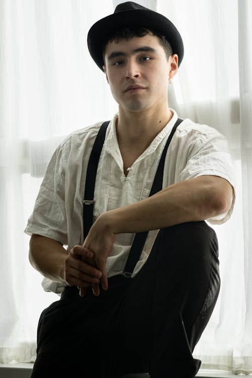 Man Sitting in Hat and White Shirt with Suspenders
