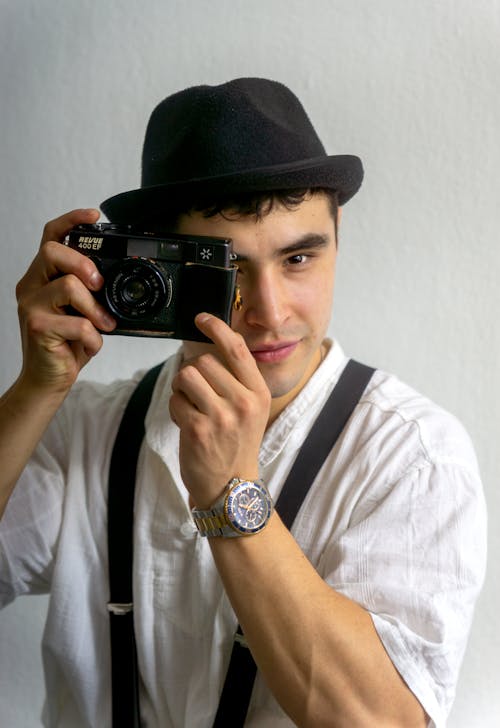 A man in suspenders holding a camera
