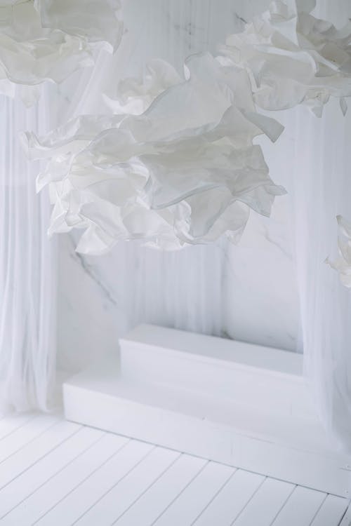 A white room with white curtains and white paper flowers