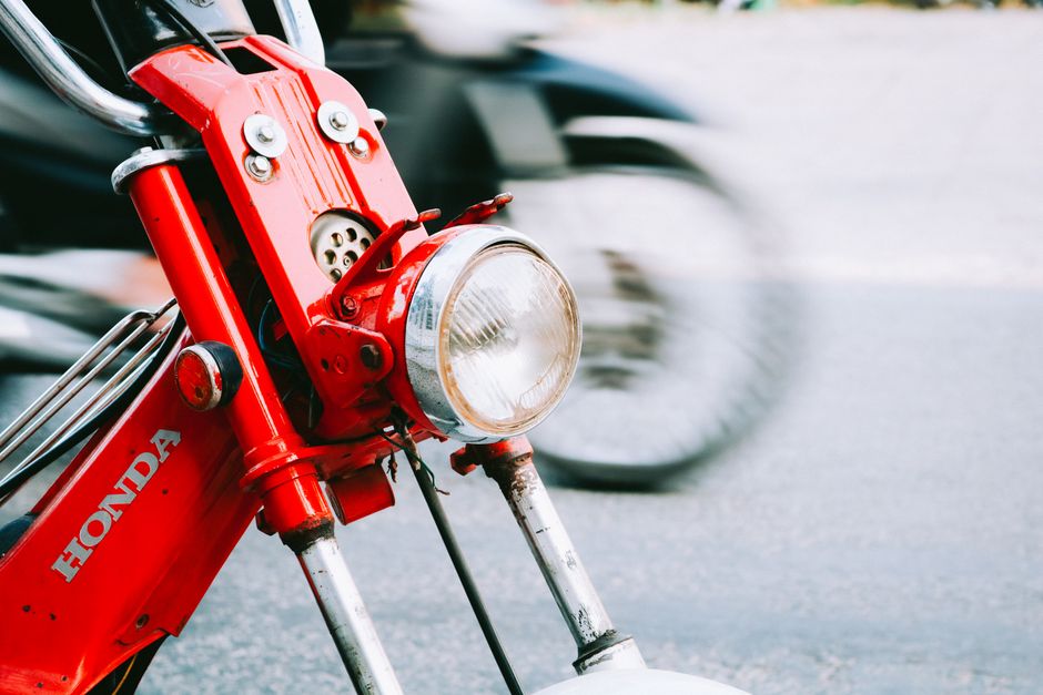 Vibrant red motorbike headlight in motion on a street in Vietnam.