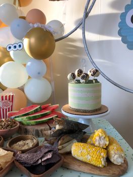 Colorful birthday party setup with balloons, cake, and assorted snacks on a table.
