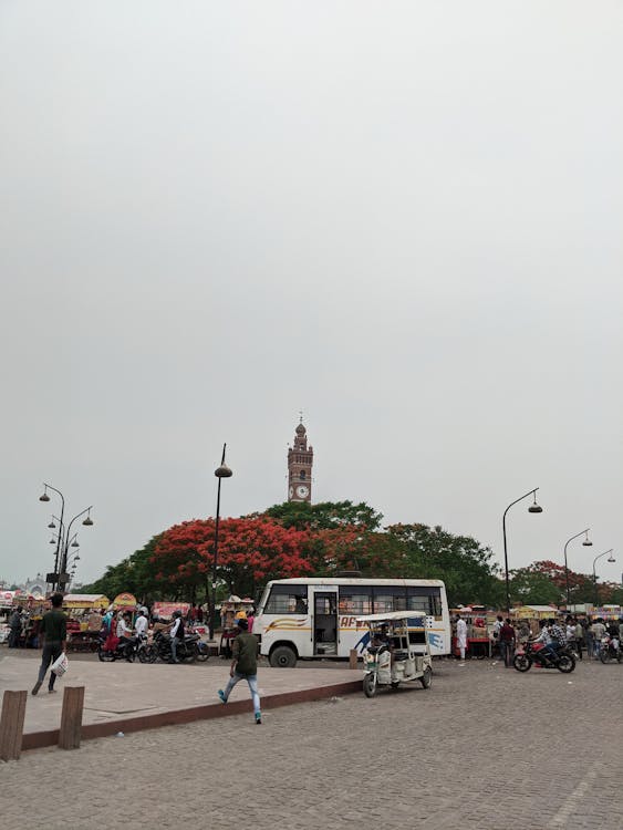 A bus is parked in a plaza with people walking around