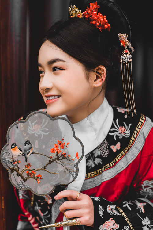 Free A beautiful portrait of a smiling woman in traditional Vietnamese dress, holding a decorative fan. Stock Photo