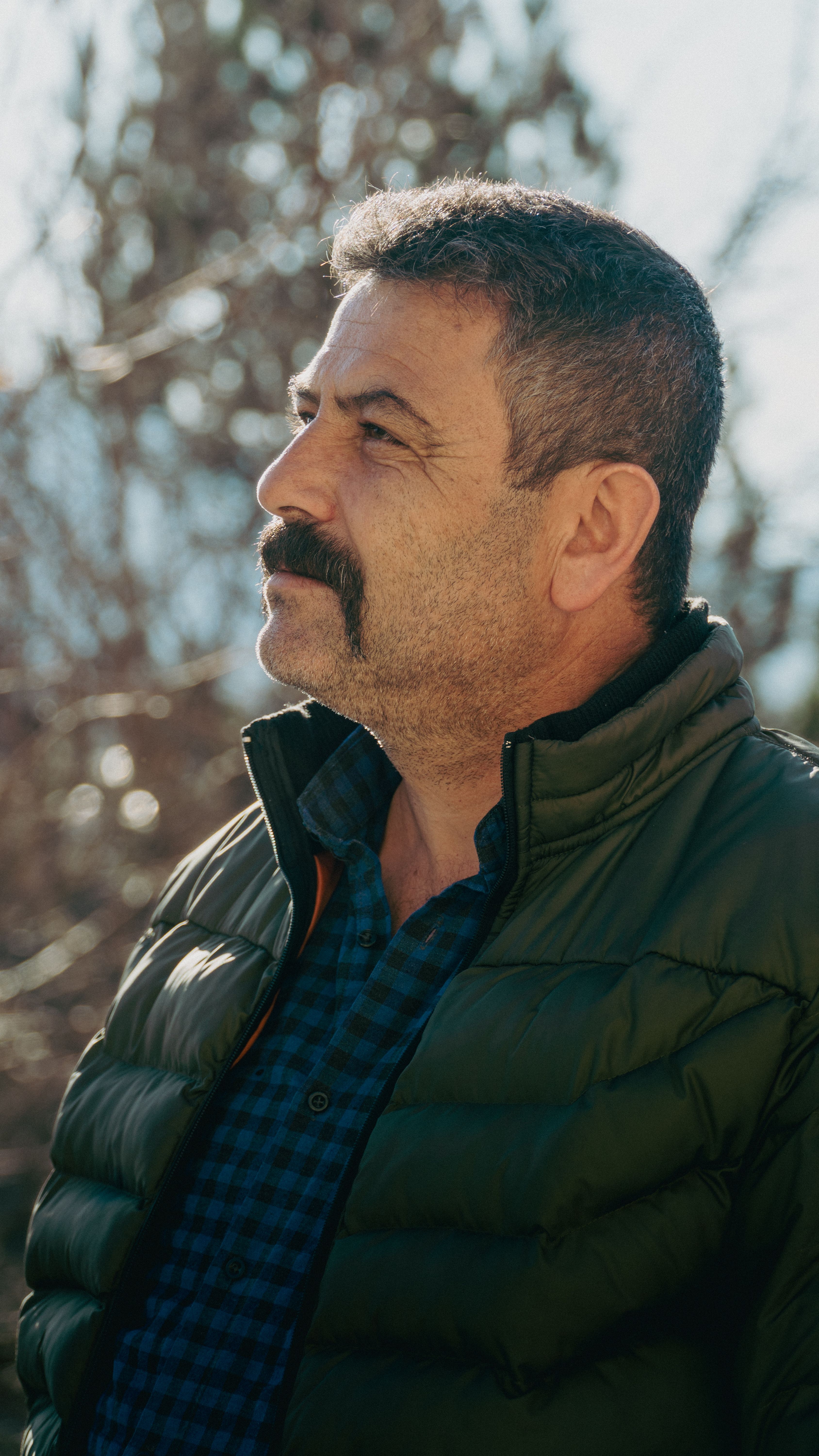 Portrait of a middle-aged man with a mustache in a winter jacket, gazing outdoors.