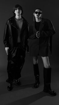 Stylish models pose in edgy black attire in a dramatic monochrome setting.