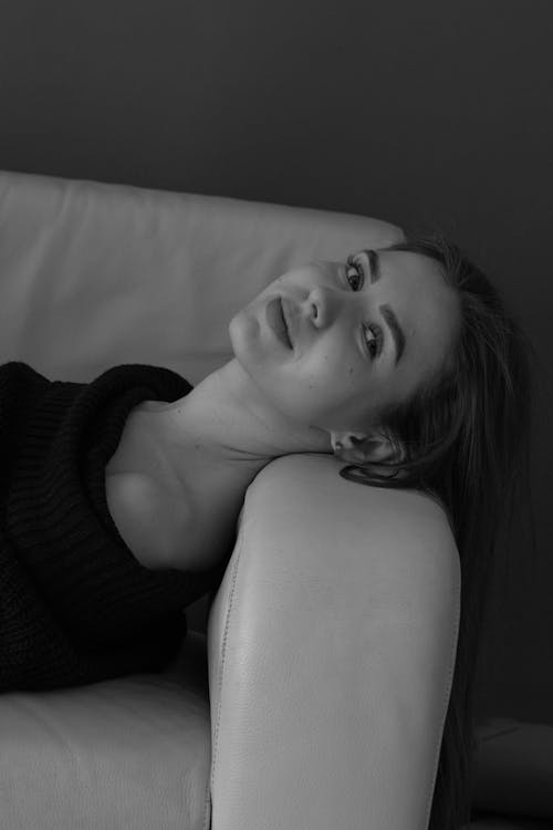 A woman laying on a couch in black and white