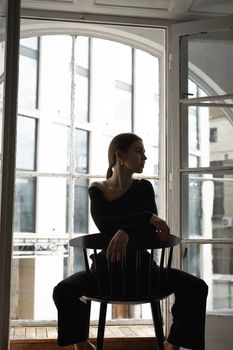 A stylish woman sitting on a chair in a modern urban setting, capturing fashion and elegance.