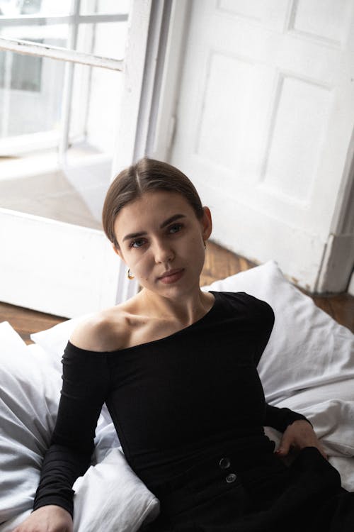 A woman in a black top sitting on a bed