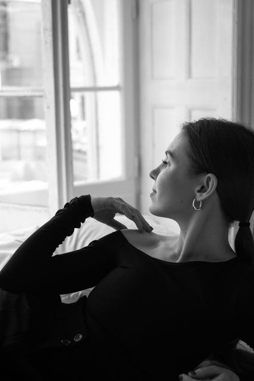 A woman in a black dress sitting on a window sill