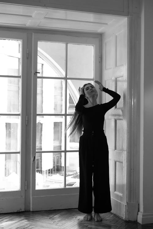 A woman in black and white standing in front of a window