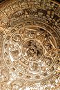 Close-up of a detailed Aztec calendar carved in copper, showcasing intricate designs and cultural significance.