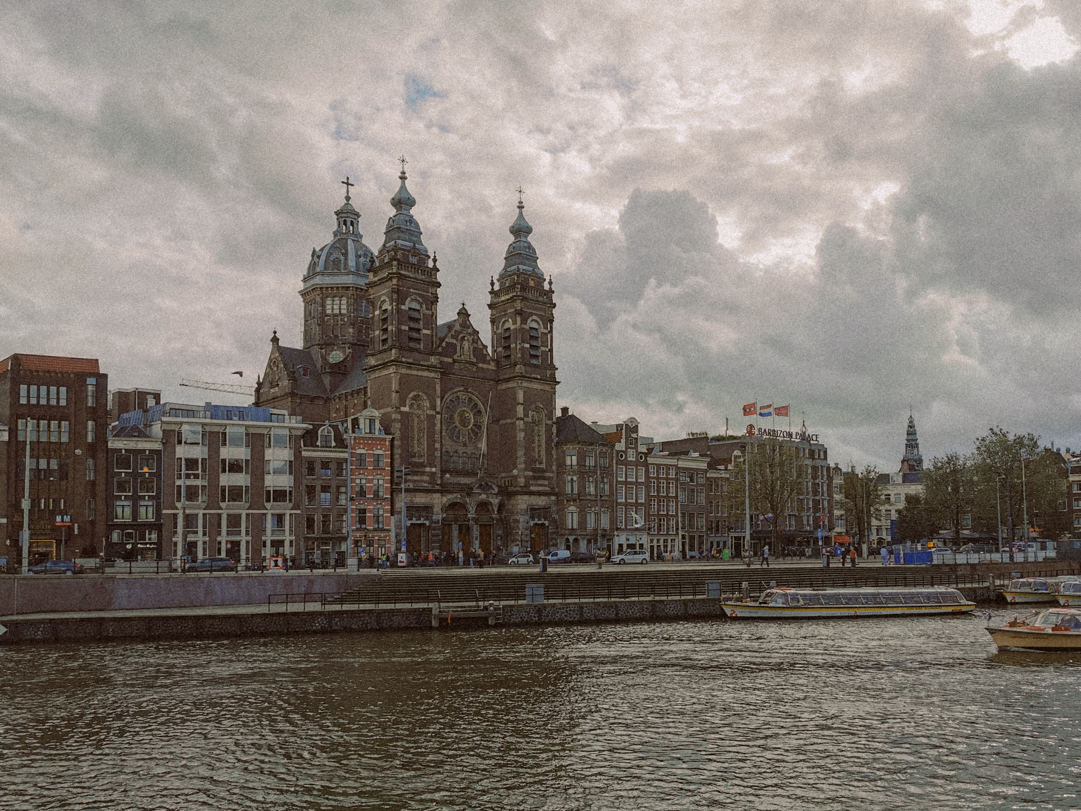 Historic Basilica of Saint Nicholas in Amsterdam with cloudy skies and canal view.