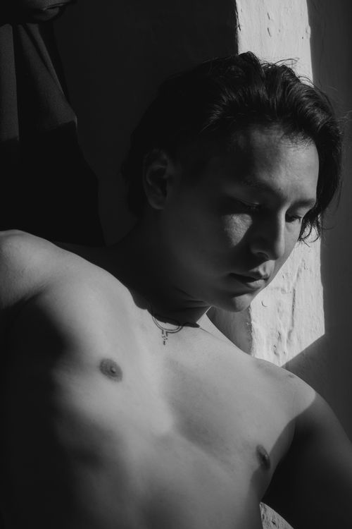 Free Dramatic black and white portrait of a shirtless young man with eyes closed, casting shadows. Stock Photo