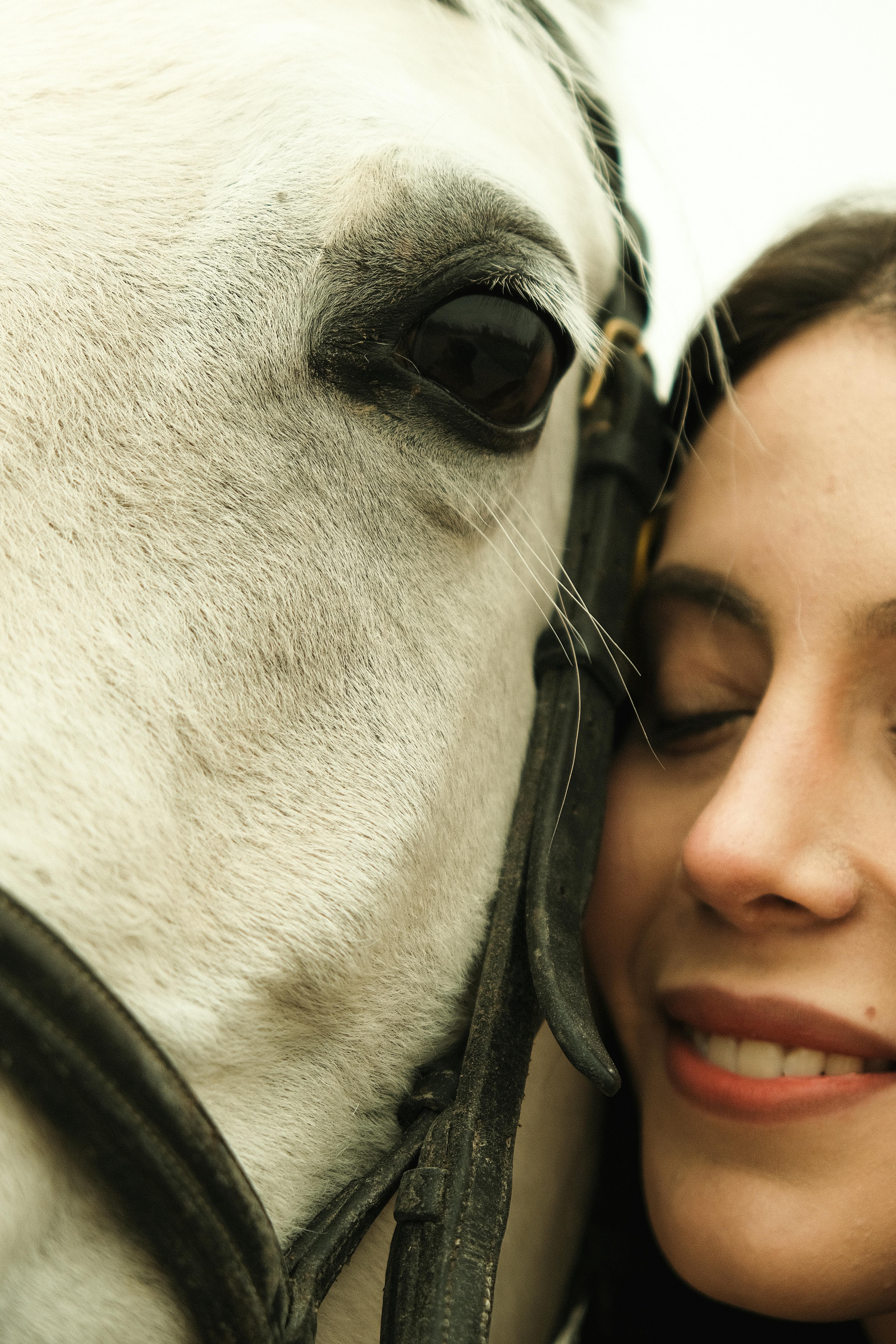 Intimate portrait of a woman affectionately hugging a white horse in Ankara, Türkiye.