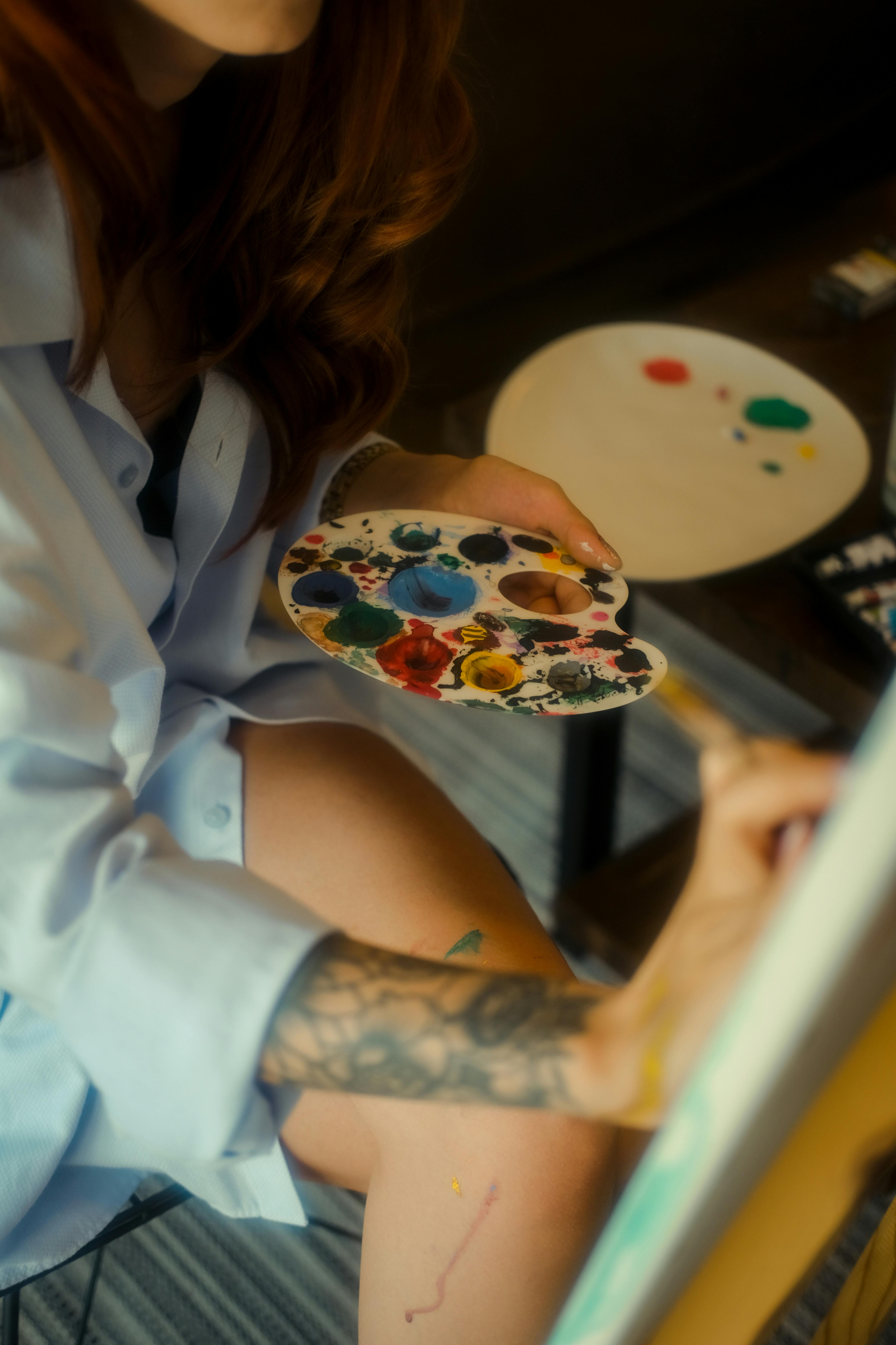 Woman artist creatively mixing colors on her palette for a painting.