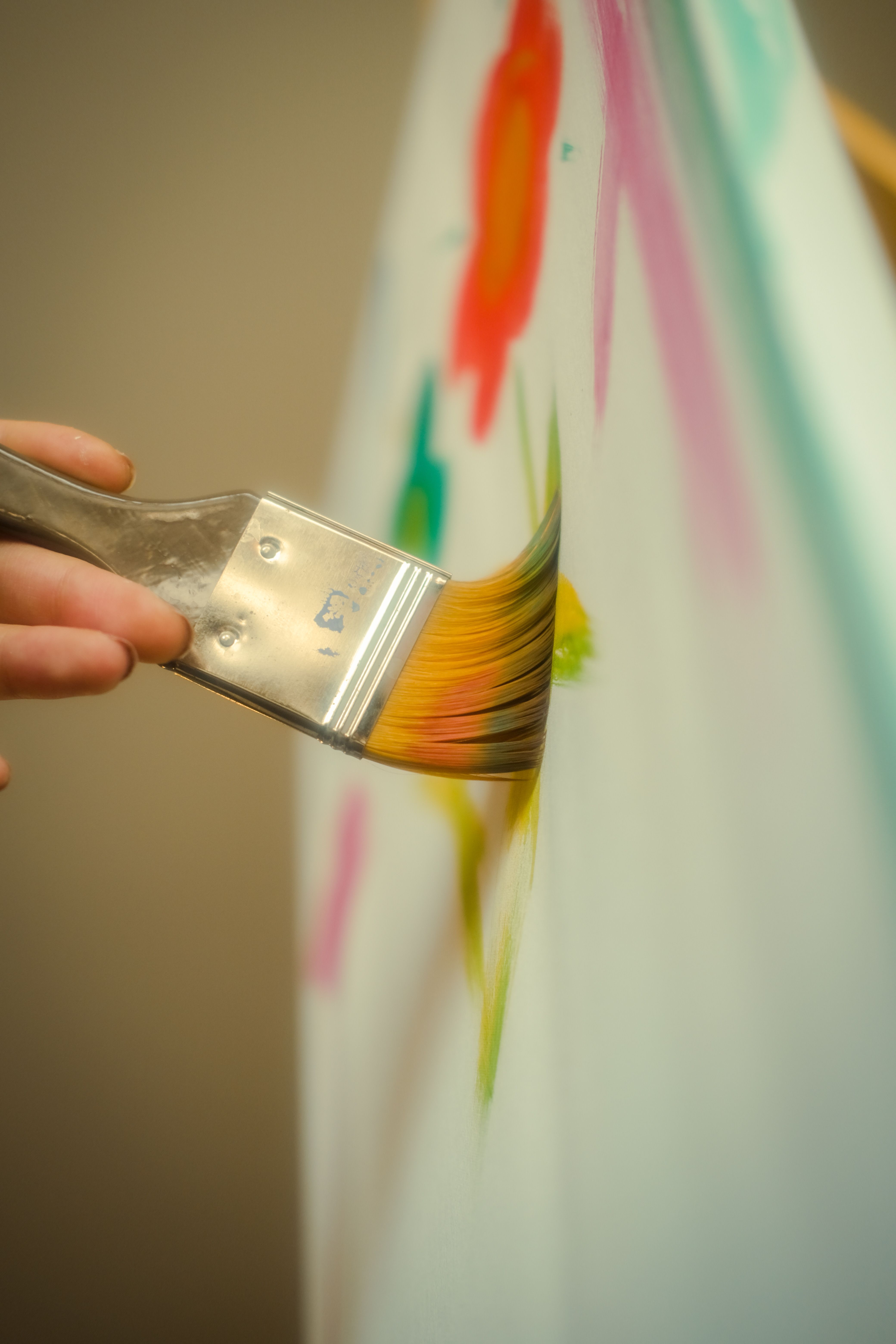 artist painting a colorful abstract canvas in a sunlit modern studio, close-up of hands with paint brushes