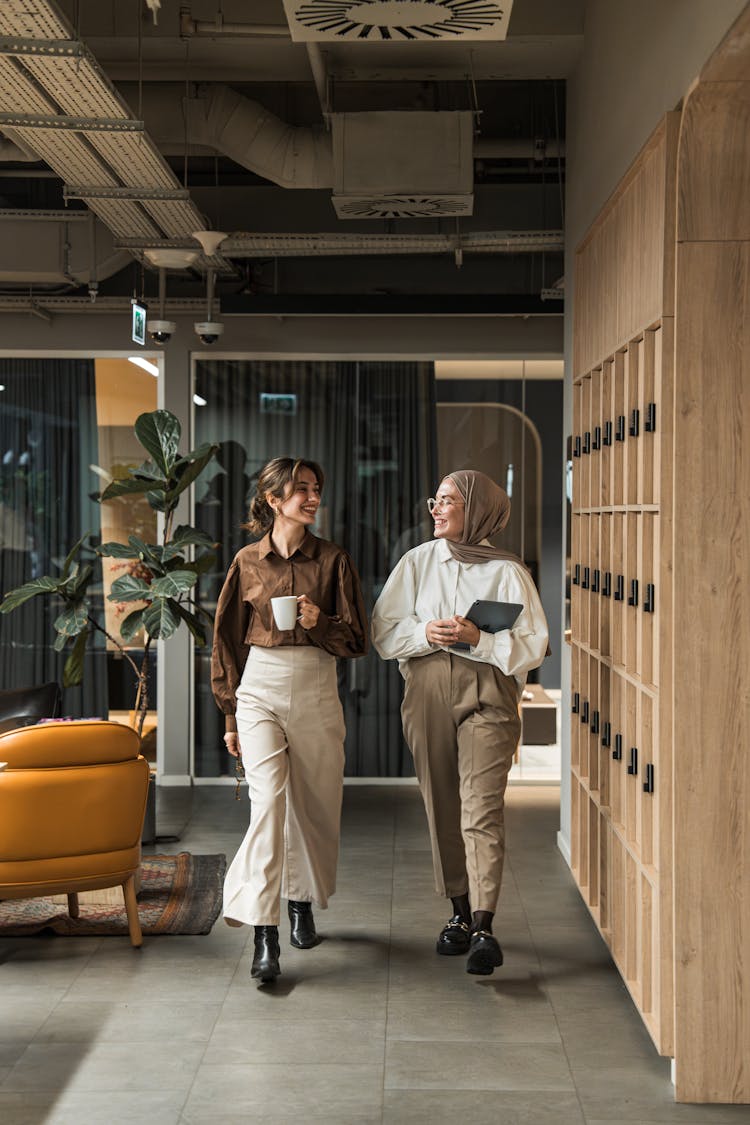 Two Young Woman Walking On The Hall Of The Office