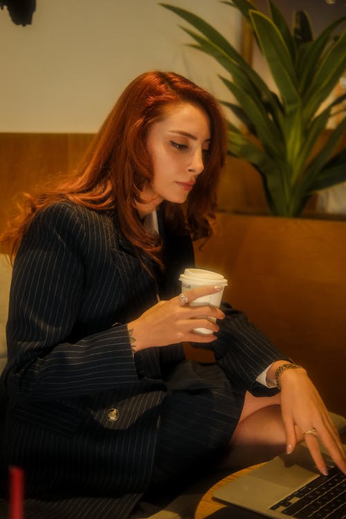 Redhead Woman Sitting with Cup and Working