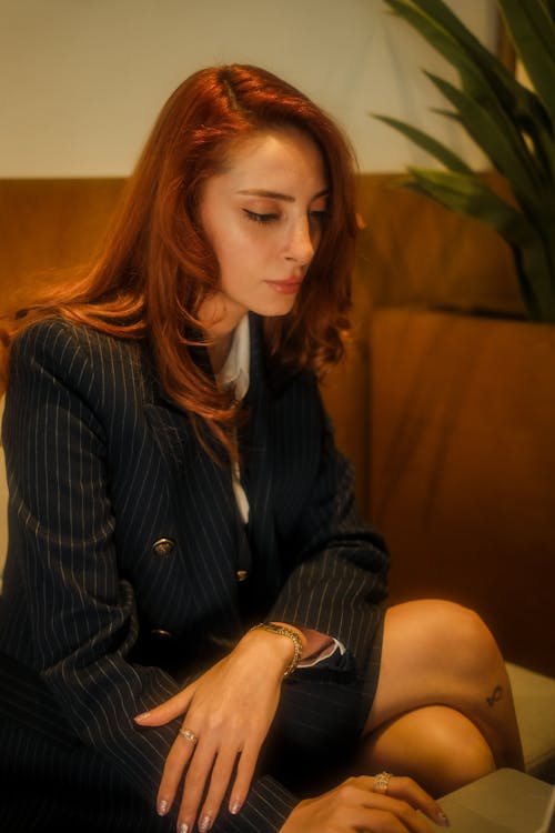 A woman in a suit sitting on a couch with her laptop