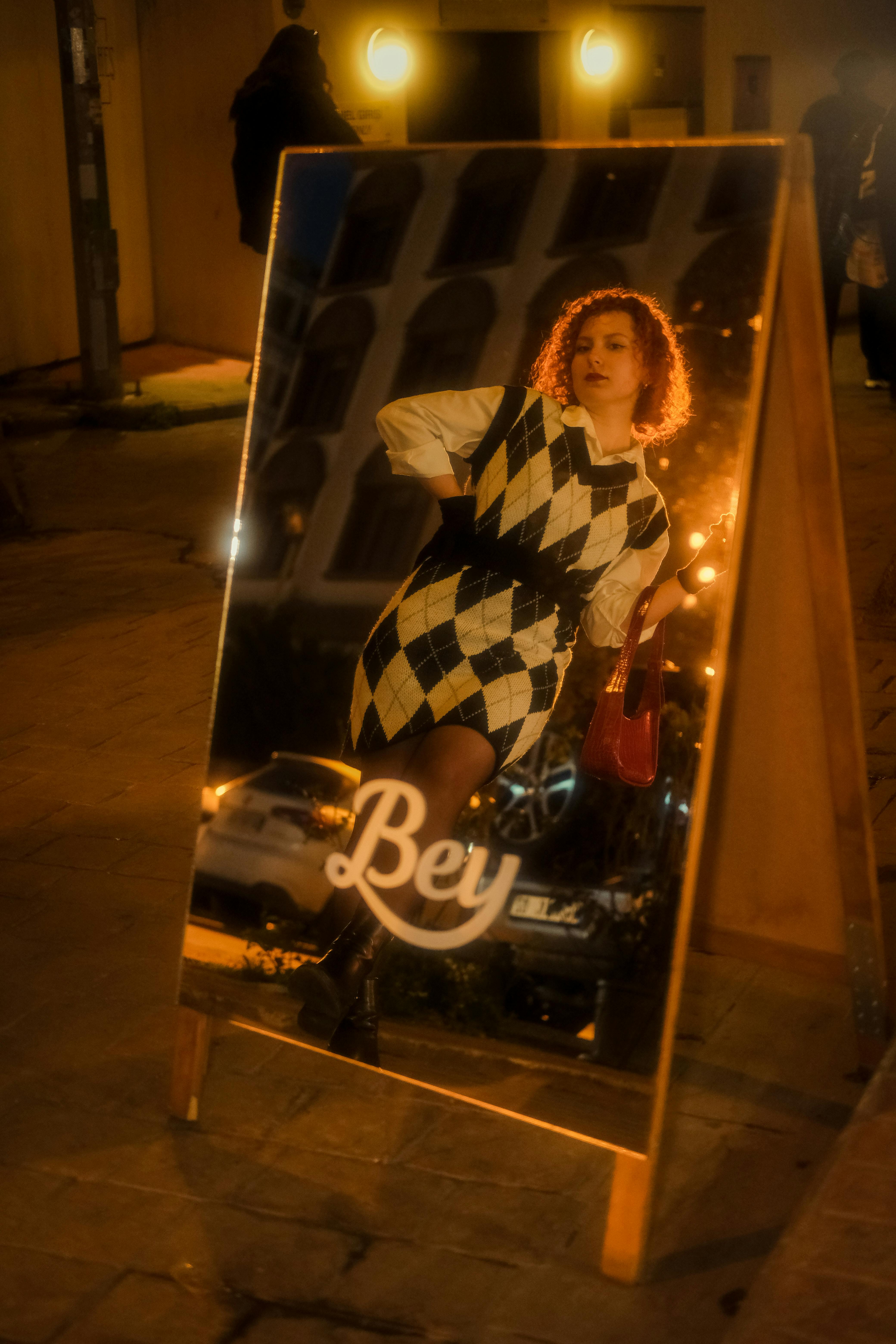 Free Artistic nighttime reflection of a woman in a city setting captured in a mirror. Stock Photo