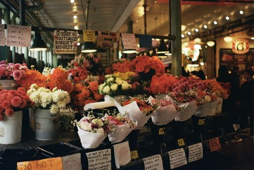 Free Vibrant flower bouquets at a bustling indoor market stall with warm lighting. Stock Photo