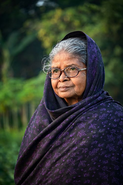 Free Portrait of a senior woman with glasses wrapped in a patterned scarf outdoors. Stock Photo
