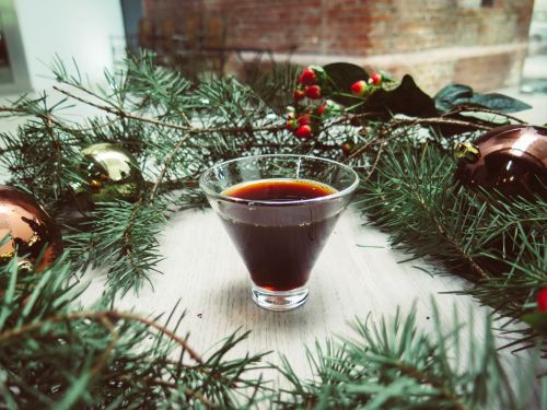 Free A glass of dark holiday drink encircled by Christmas decorations and pine greenery on a table. Stock Photo