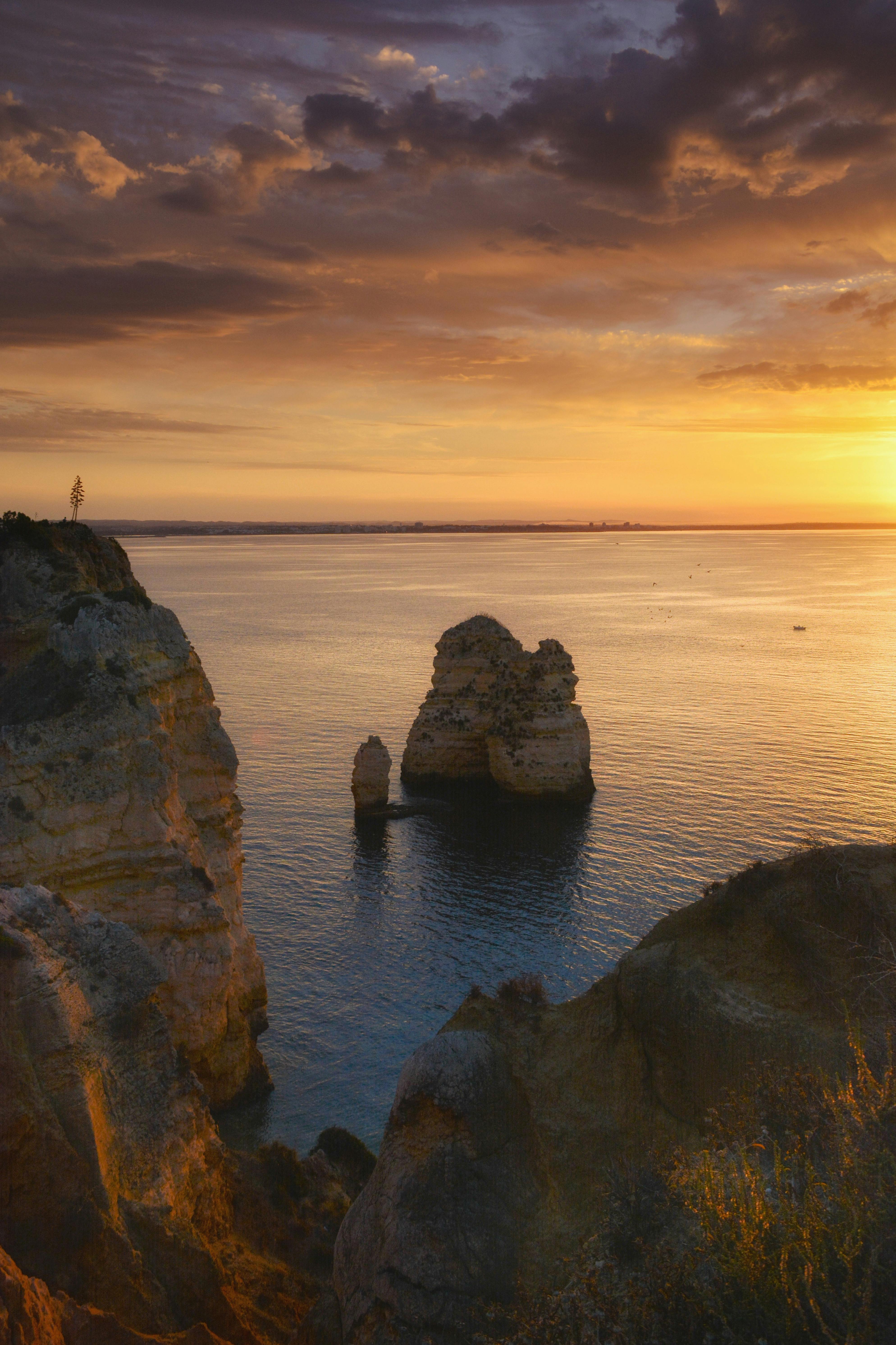 Stunning sunset over sea cliffs with rock formations and dramatic sky.