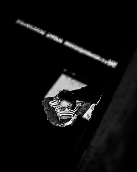 Aerial view of a woman in sunlight, cast in stark shadows.