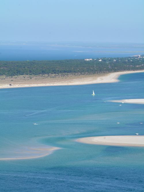 Free Scenic aerial view of Sesimbra's coastline, featuring turquoise sea and a sailboat. Stock Photo