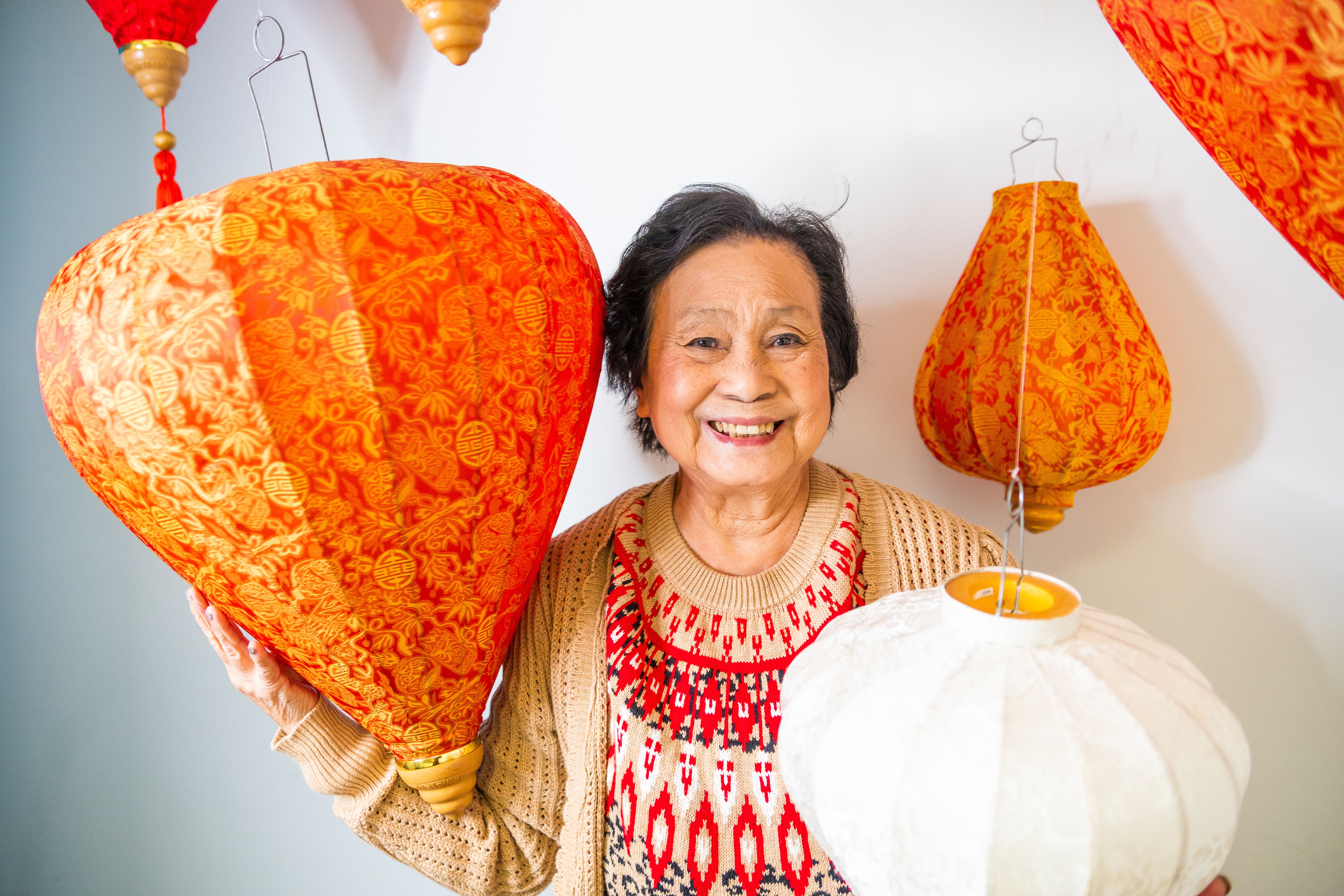 An older woman holding up some paper lanterns · Free Stock Photo