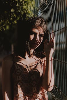 一个女人在篱笆前摆出戏剧性的阴影，营造出艺术效果