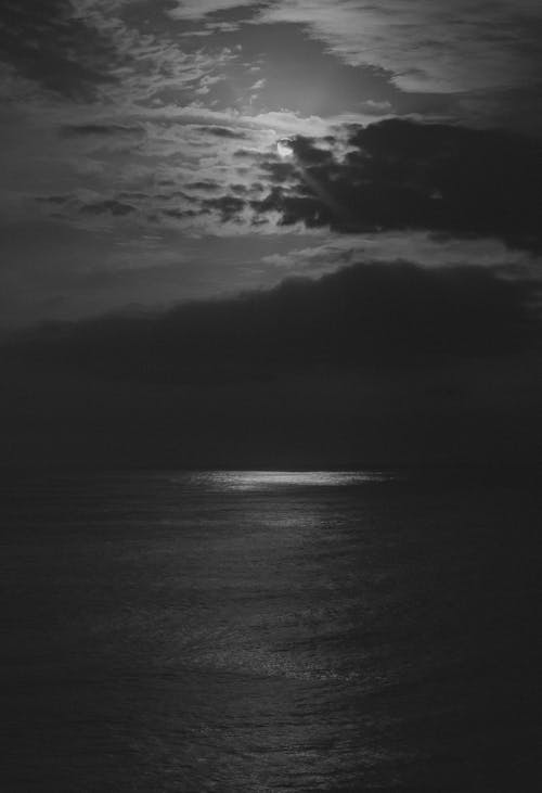 A black and white photo of the ocean with the moon