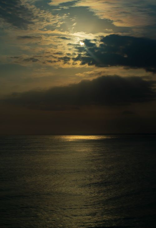 Free A tranquil ocean sunset with dramatic clouds and warm hues, creating a serene atmosphere. Stock Photo