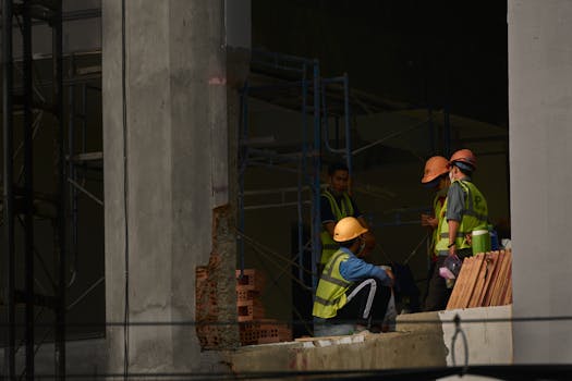 Construction workers wearing helmets and reflective vests at a site in Can Tho, Vietnam, discussing a project.