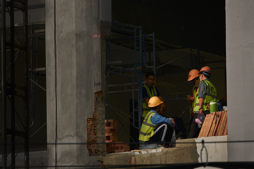 Free Construction workers wearing helmets and reflective vests at a site in Can Tho, Vietnam, discussing a project. Stock Photo