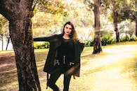 一位时尚女士在阳光明媚的公园里优雅地摆着姿势，展现出自然的优雅与魅力