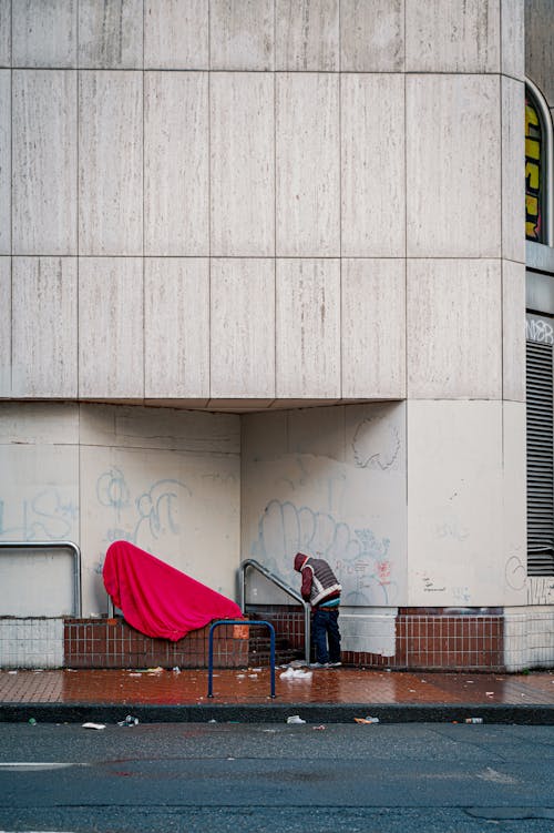 A person is sitting on the ground next to a building