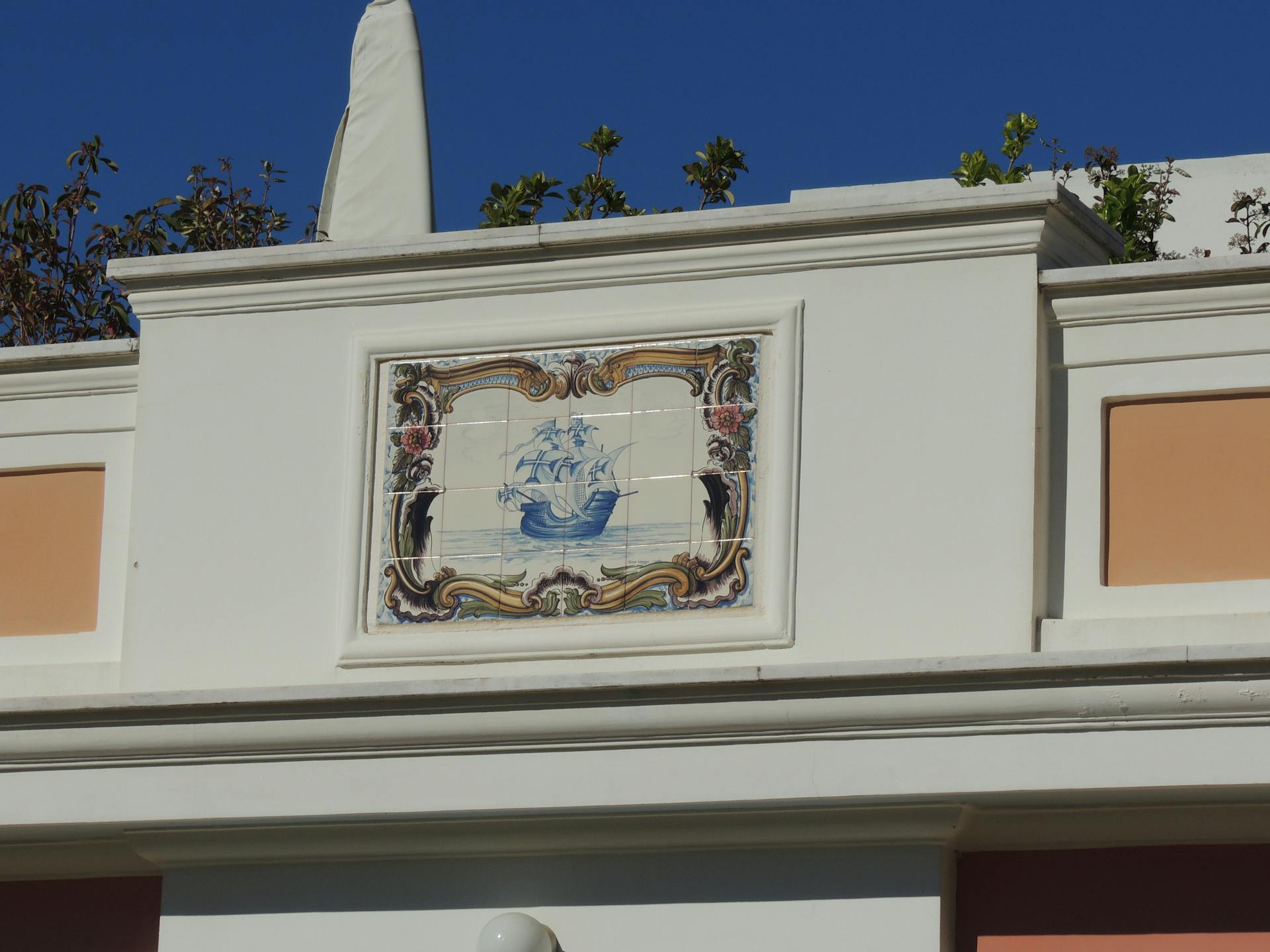 An artistic mosaic of a ship on an exterior building facade with vibrant colors.