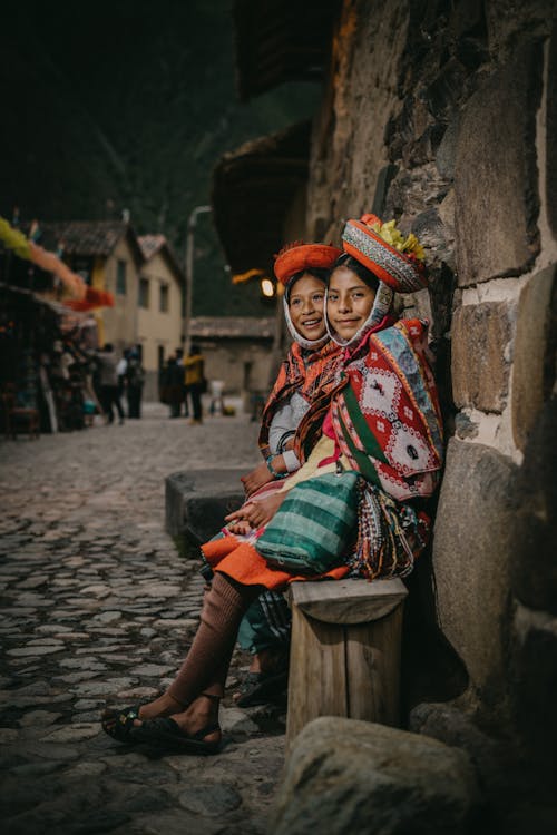 Peruvian Girls Wearing Traditional Clothing, Sitting by a Wall