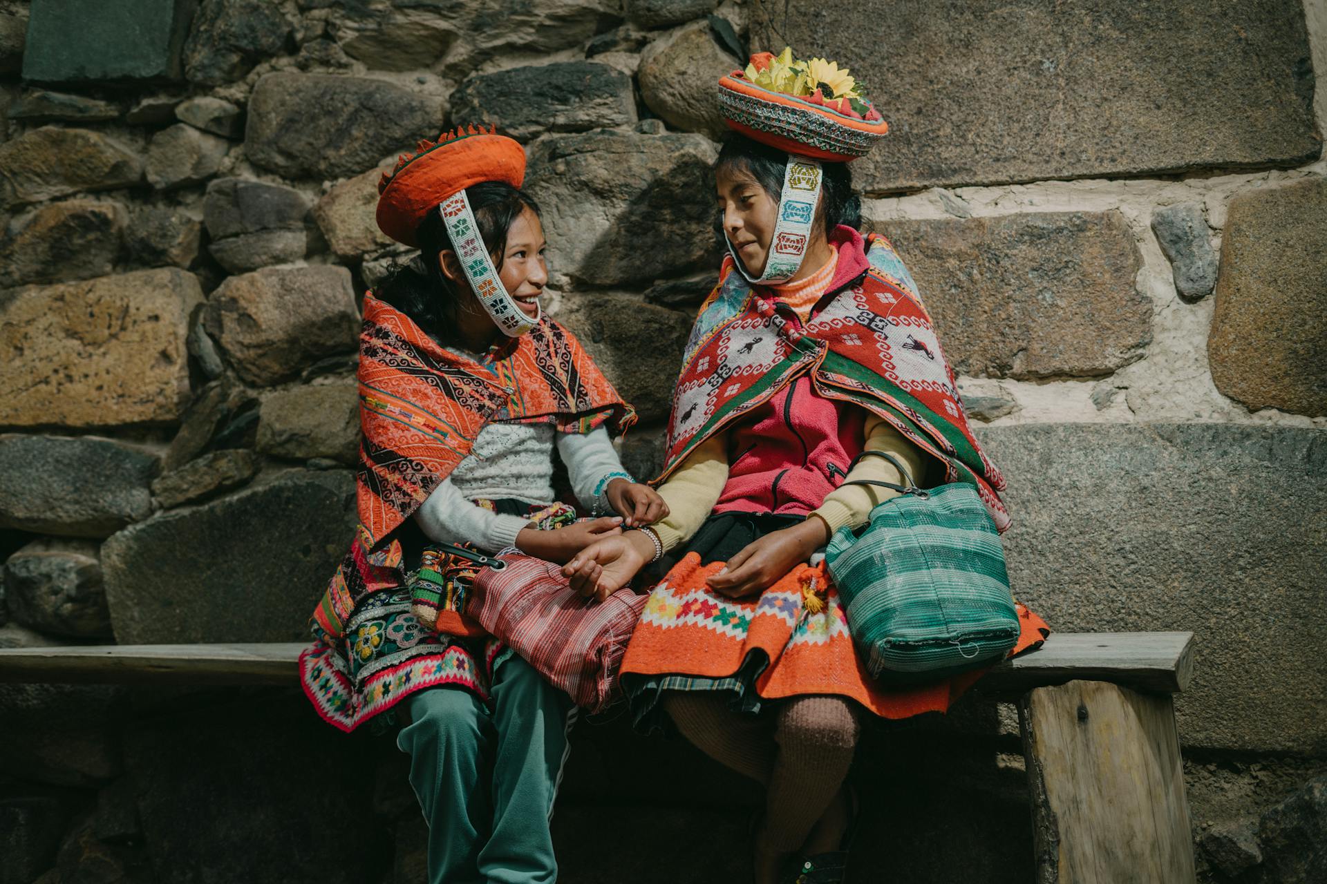 Peruvian Girls Wearing Traditional Clothing, Sitting by a Wall