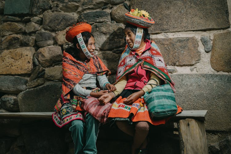 Peruvian Girls Wearing Traditional Clothing, Sitting By A Wall