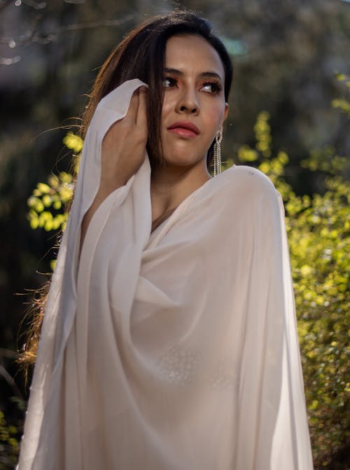 A woman in a white shawl is posing for the camera
