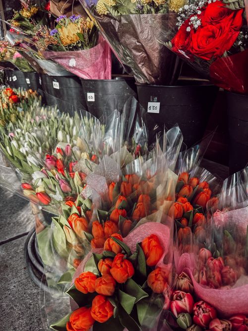 Free Vibrant floral display featuring tulips and roses at a New York City market. Perfect for street photography enthusiasts. Stock Photo