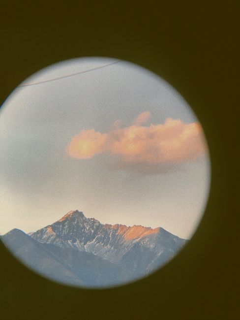 Beautiful mountain landscape seen through a circular frame, with a pink cloud at sunset.
