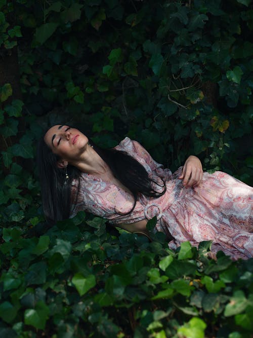 Brunette Woman in Dress Lying Down among Leaves
